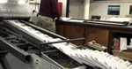 A newspaper press with lots of newspapers being printed.